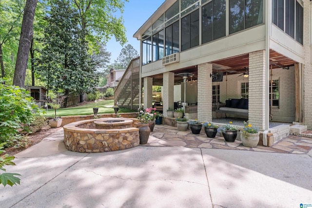 view of patio featuring a sunroom, a ceiling fan, a fire pit, and stairs