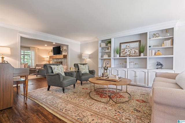 living room featuring ornamental molding, dark wood-style floors, built in features, and a fireplace