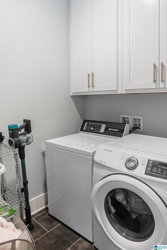 laundry room with baseboards, cabinet space, washer and clothes dryer, and dark tile patterned flooring