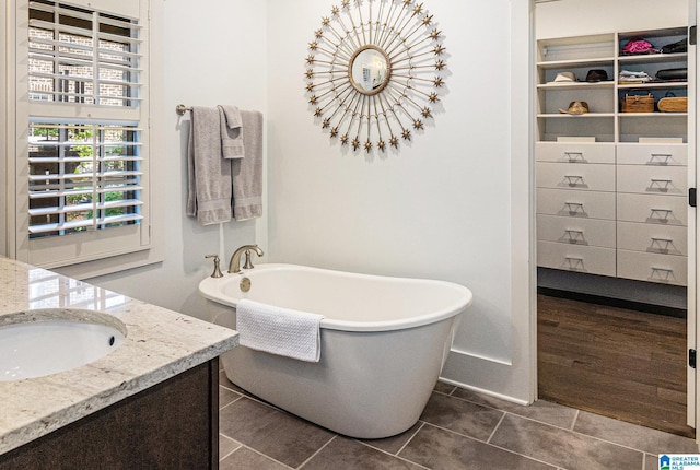 full bathroom with a freestanding tub, vanity, and tile patterned floors