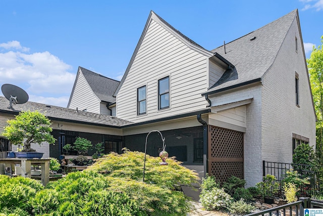 rear view of property featuring a sunroom, fence, and brick siding