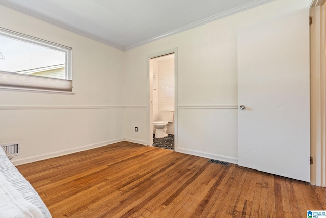 unfurnished bedroom with baseboards, wood finished floors, visible vents, and ornamental molding