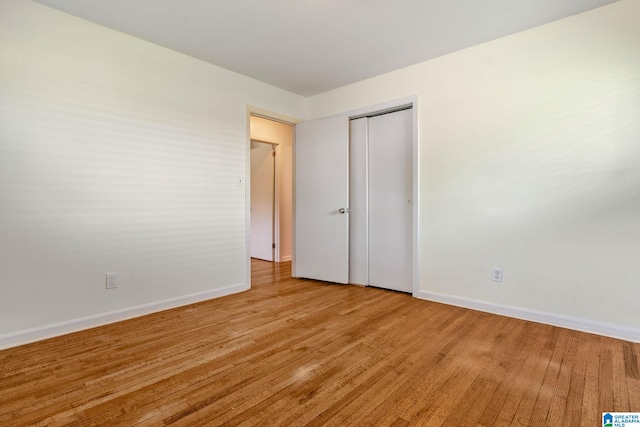 unfurnished bedroom featuring light wood-style flooring, a closet, and baseboards