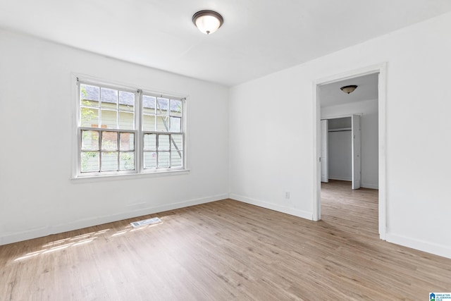 spare room with baseboards, light wood finished floors, and visible vents