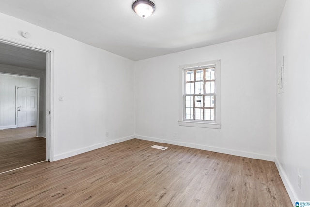 spare room featuring baseboards, wood finished floors, and visible vents