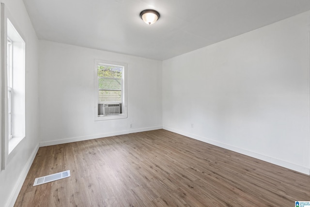 spare room featuring visible vents, baseboards, wood finished floors, and cooling unit