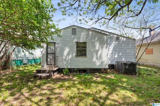 rear view of property featuring a yard and central AC unit