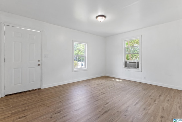 empty room with baseboards, wood finished floors, and cooling unit