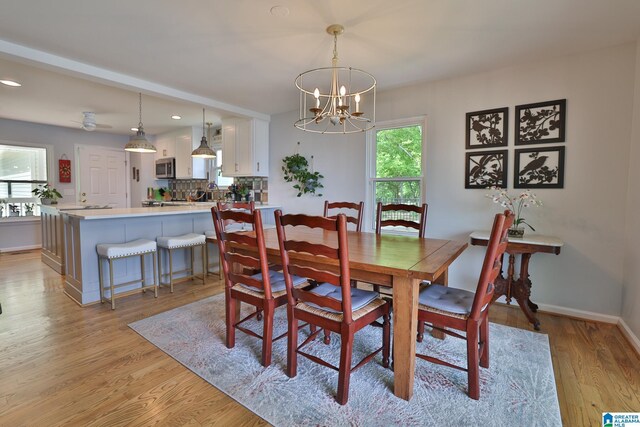 dining space with recessed lighting, baseboards, a notable chandelier, and light wood-type flooring