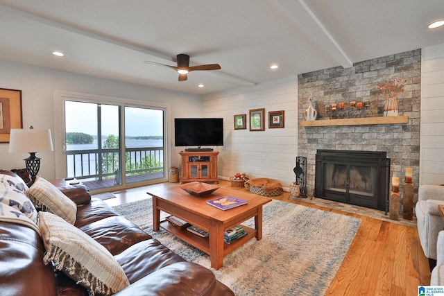 living room with a ceiling fan, wood finished floors, wooden walls, a brick fireplace, and recessed lighting