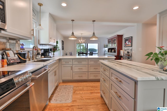 kitchen with recessed lighting, stainless steel appliances, a sink, a peninsula, and light wood-style flooring