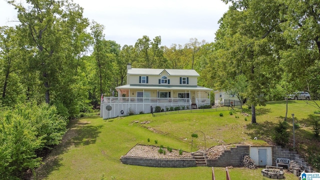 rear view of house with a lawn, covered porch, stairs, and a wooded view