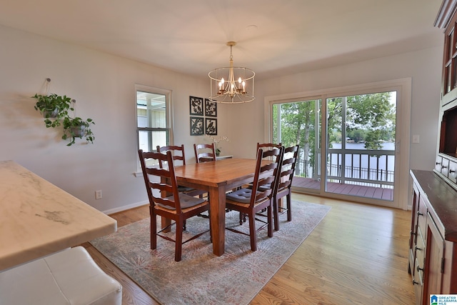 dining room featuring a chandelier, light wood finished floors, and baseboards