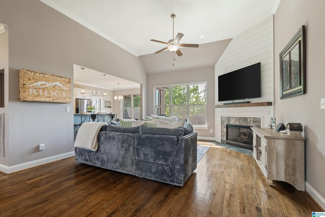 living area featuring vaulted ceiling, baseboards, a ceiling fan, wood finished floors, and a fireplace