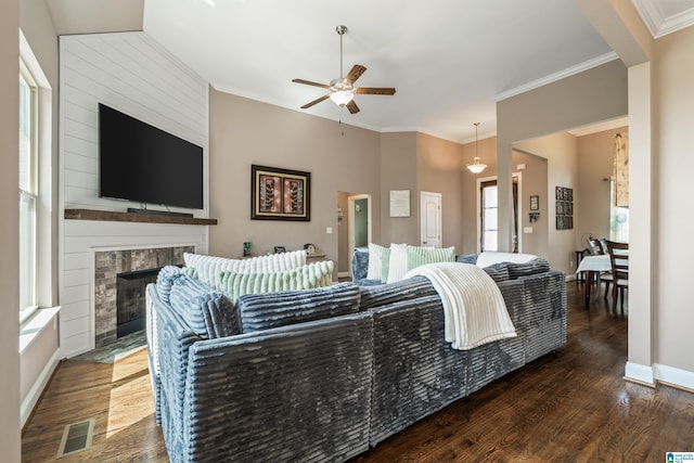 living room featuring a fireplace with flush hearth, wood finished floors, visible vents, and a ceiling fan