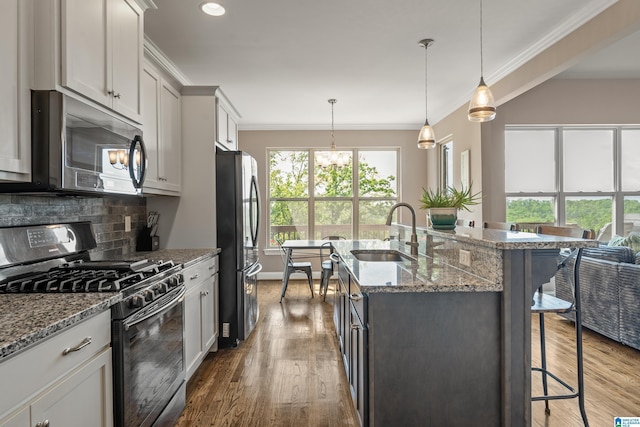 kitchen with a breakfast bar, a sink, crown molding, a kitchen island with sink, and appliances with stainless steel finishes