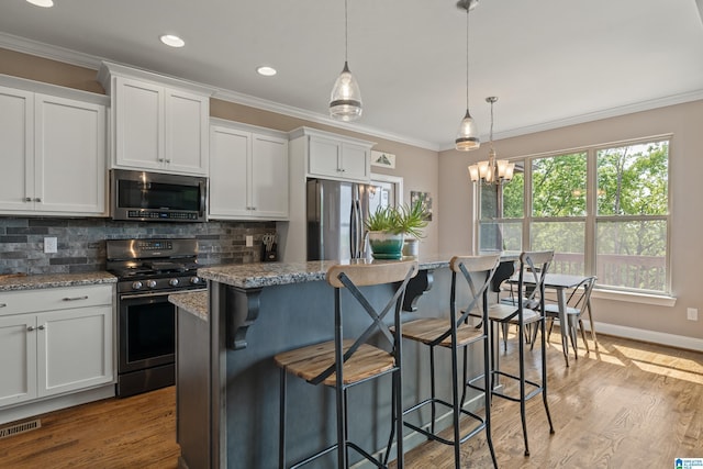 kitchen featuring stainless steel appliances, tasteful backsplash, visible vents, crown molding, and a kitchen island
