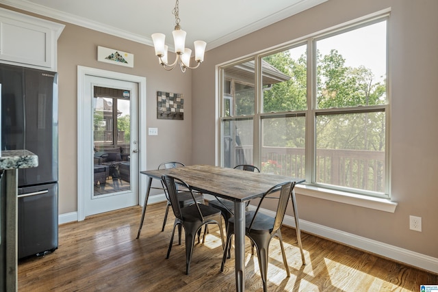 dining space with a wealth of natural light, baseboards, crown molding, and an inviting chandelier