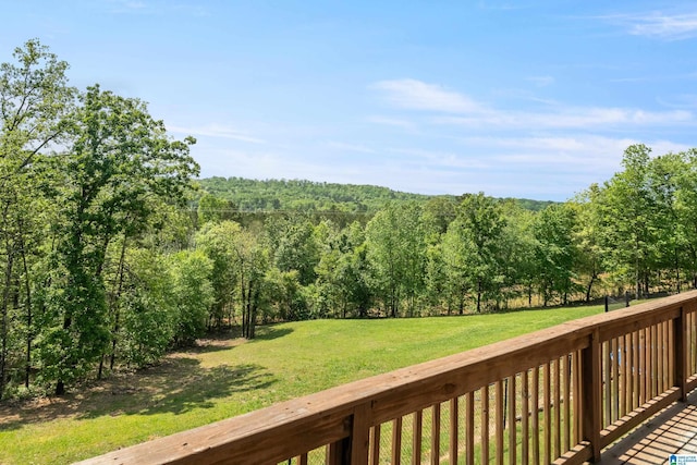 wooden terrace featuring a yard and a view of trees