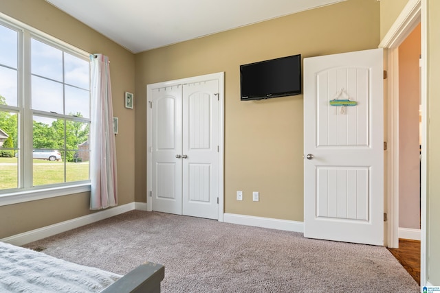 unfurnished bedroom featuring a closet, carpet flooring, baseboards, and multiple windows