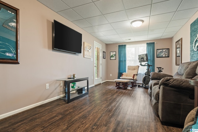 living area featuring wood finished floors, baseboards, and a paneled ceiling