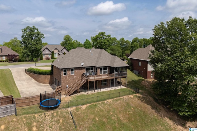 back of property with stairway, a wooden deck, a fenced backyard, and a trampoline