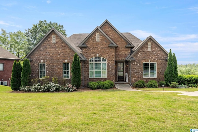 view of front of house featuring brick siding, cooling unit, a shingled roof, and a front yard