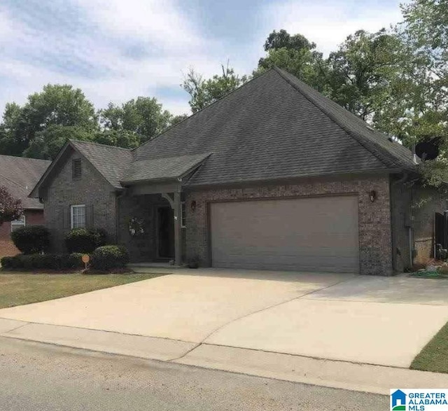 view of front of property featuring concrete driveway, brick siding, a shingled roof, and a garage
