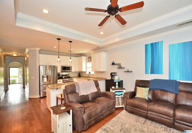 living room with visible vents, ornamental molding, arched walkways, a ceiling fan, and dark wood finished floors