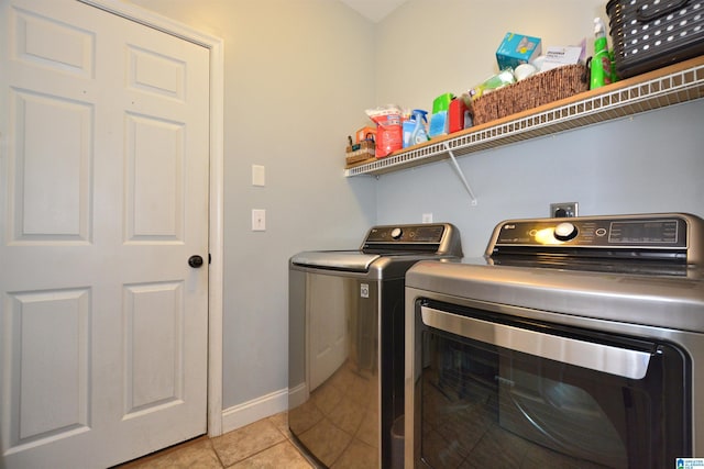 laundry area with light tile patterned floors, separate washer and dryer, baseboards, and laundry area