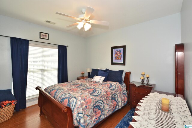 bedroom with a ceiling fan, wood finished floors, and visible vents