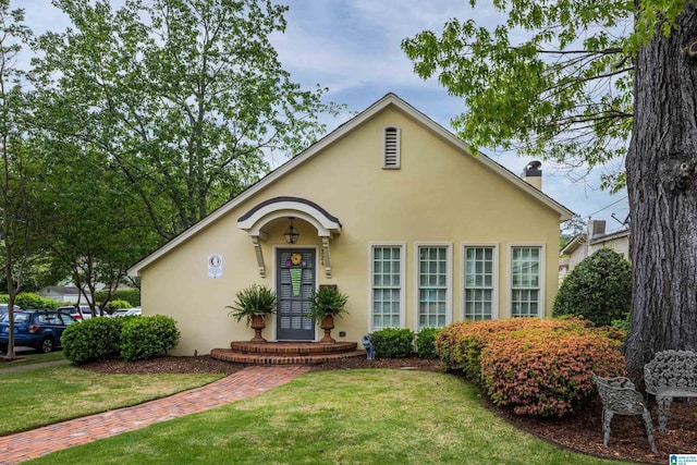 view of front of home featuring stucco siding, a front lawn, and a chimney