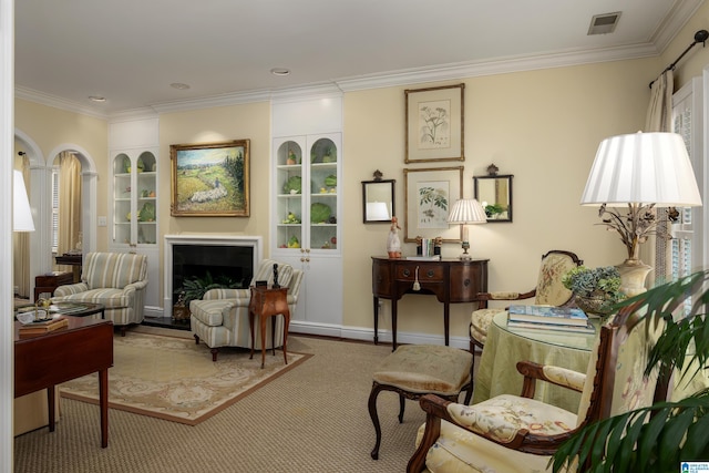 living area featuring a fireplace, built in features, visible vents, carpet, and ornamental molding