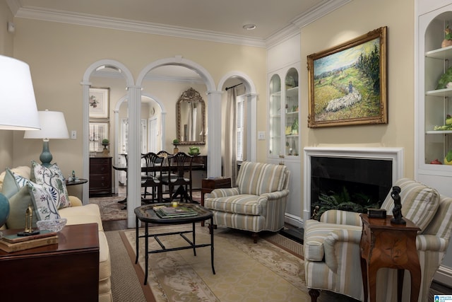 living area with a fireplace, wood finished floors, crown molding, and built in shelves