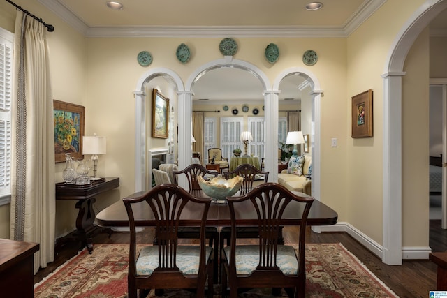 dining space featuring crown molding, dark wood finished floors, arched walkways, and ornate columns