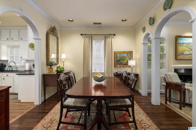 dining space with dark wood-style floors, visible vents, arched walkways, and crown molding
