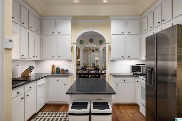 kitchen with wood finished floors, dark countertops, stainless steel appliances, and white cabinets
