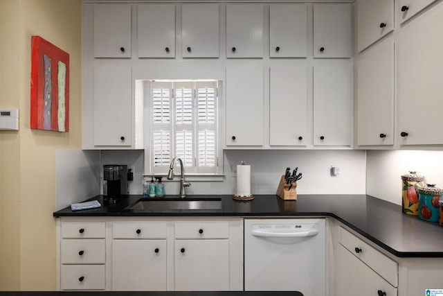 kitchen with dark countertops, dishwasher, white cabinetry, and a sink