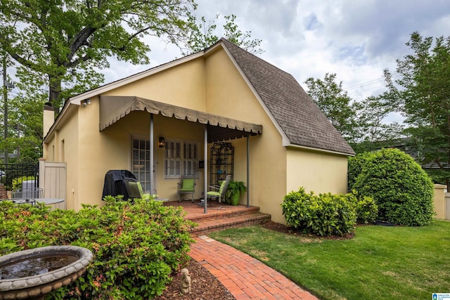 back of property with a yard, a chimney, roof with shingles, stucco siding, and fence