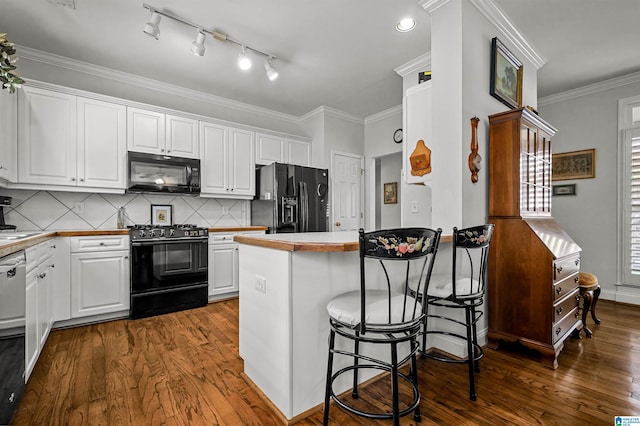 kitchen with white cabinets, black appliances, a peninsula, and dark wood-type flooring