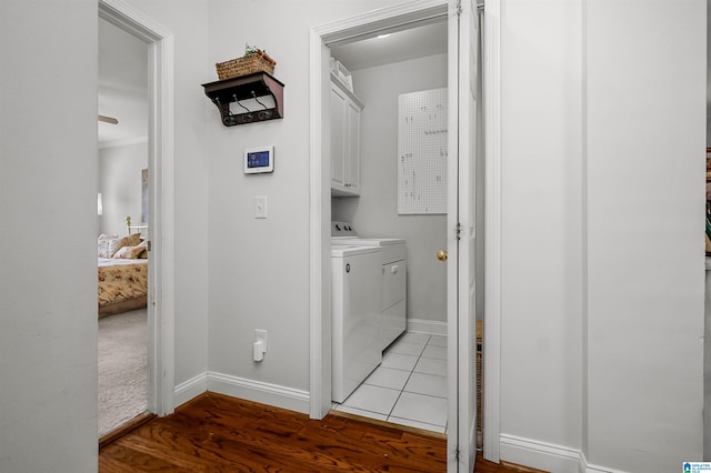 laundry area featuring baseboards, light wood-style floors, cabinet space, and washing machine and clothes dryer