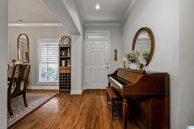 foyer entrance with baseboards, visible vents, wood finished floors, and crown molding