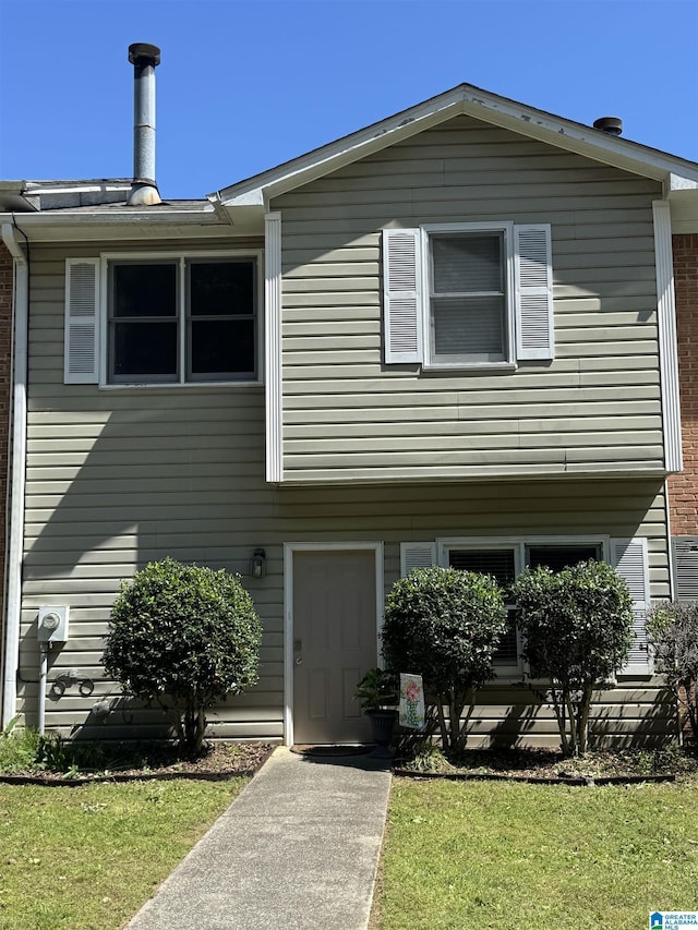 view of front facade with brick siding and a front lawn