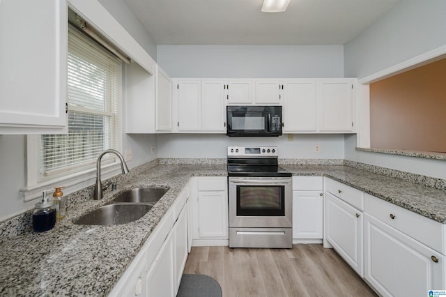 kitchen with electric range, black microwave, white cabinetry, and a sink