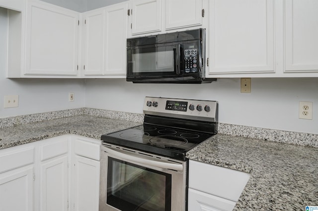 kitchen featuring white cabinets, electric range, black microwave, and light stone counters
