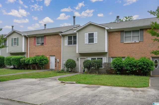 townhome / multi-family property with brick siding and a front lawn