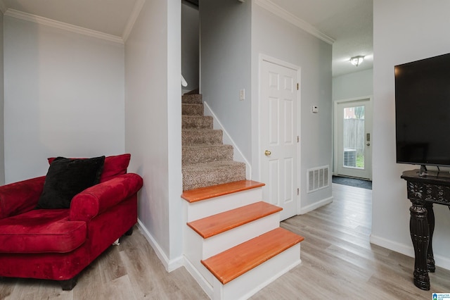 staircase featuring baseboards, visible vents, ornamental molding, and wood finished floors