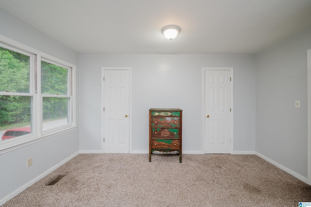 empty room with baseboards, carpet flooring, and visible vents