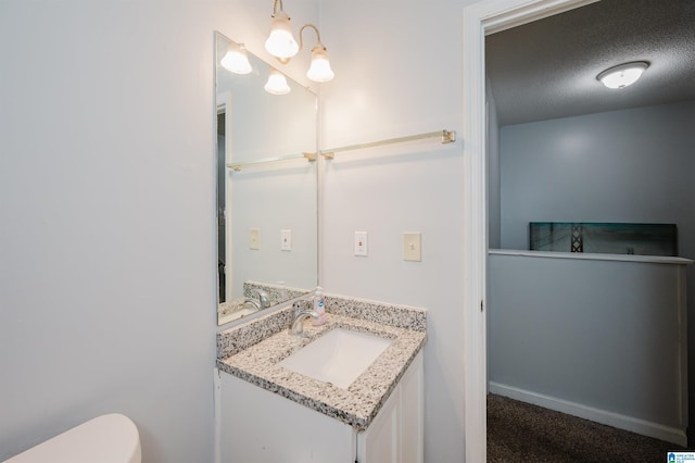 half bathroom with toilet, a textured ceiling, baseboards, and vanity