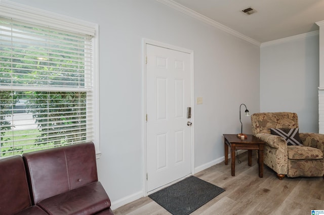 entryway featuring baseboards, ornamental molding, light wood-style flooring, and visible vents